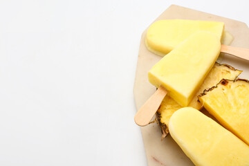 Board with tasty pineapple popsicle on white background
