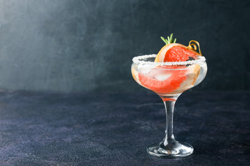 Glass of cold gin tonic and orange slices on dark background