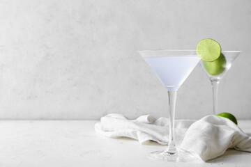 Glasses of tasty margarita cocktail on light background