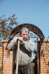 Fototapeta na wymiar An elderly man leaned on the handle of a shovel for a short rest between work