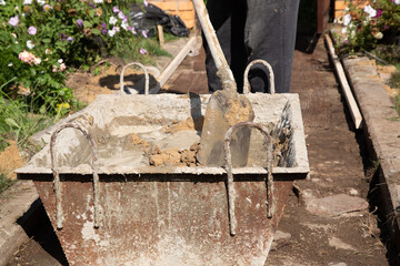 A man unloads sand into a cement mixture for pouring a garden path
