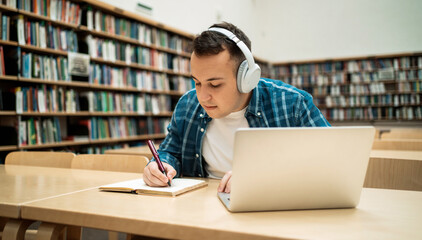 Reads an e-book in the university library. A millennial man is studying at the institute. Surf the...