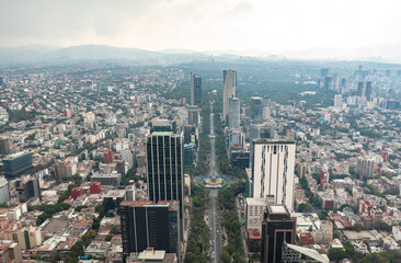 Fototapeta na wymiar Aerial view of the Angel of Independence surrounded by greenery and commercial and financial building in Mexico City during day