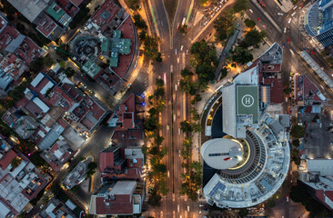 Birds eye view of cars running on street surrounded by commercial building with helipad and residential buildings in Mexico City at evening