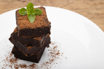 Chocolate brownies with pepper mint leaf on top on white plate background