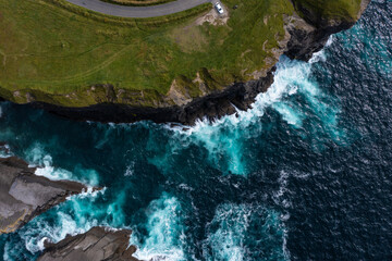 Birds eye view of the famous Moher Cliff in Ireland with car parked at end street on mountain with...