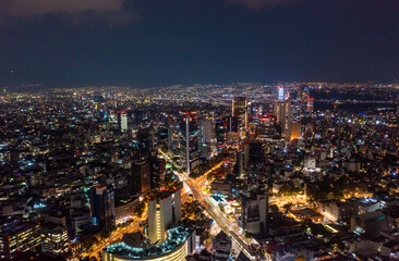 Aerial view of beautiful buildings with illuminated lightings shining in Mexico City against dark black sky at night