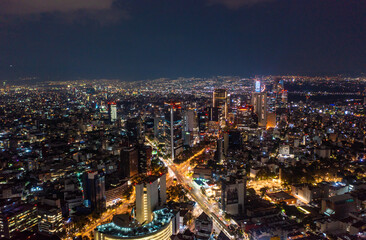 Obraz premium Aerial view of beautiful buildings with illuminated lightings shining in Mexico City against dark black sky at night
