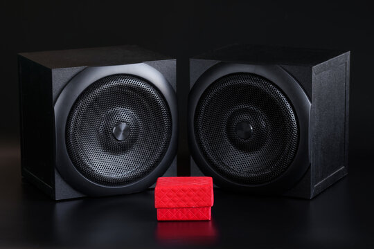 Red gift box and two single-way audio speakers on a black background. Hi-end analog acoustics of a studio, music center or home theater. Musical gift concept