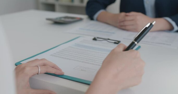 Close-up hand asia people woman fill rent loan form write legal debt letter at lawyer home office. Happy female life buy or sell new house deal from real estate sale agent. Tax advice talk and smile.