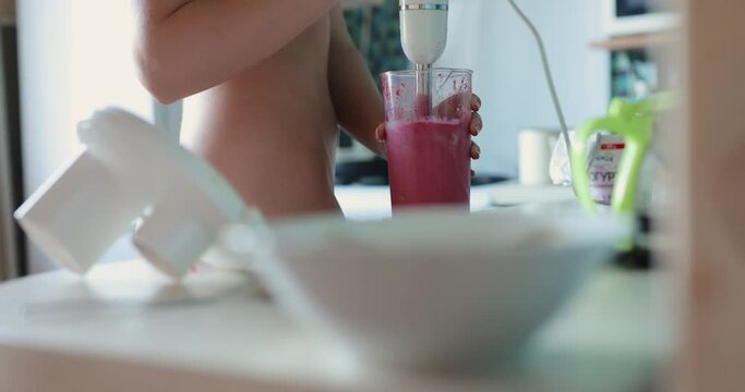 Unrecognizable naked woman mixing smoothie in blender at kitchen