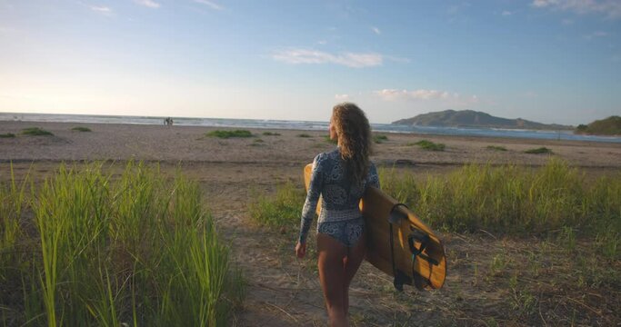 Slow Motion Shot Of Female Surfer Holding Surfboard While Walking On Beach - Tamarindo, Costa Rica