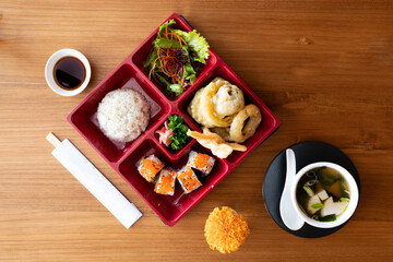 Set of traditional Japanese food: hot soup, boiled white rice, sushi rolls on wooden table. Dishes of Japanese cuisine, from above, asian dinner or lunch template