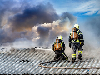 Emergency. Firefighters extinguish the flame on the roof of the building. Roofing houses covered...