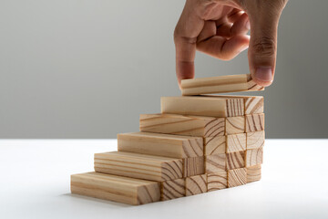 Hand arranging wood block stacking as step stair or ladder career path concept for business growth...