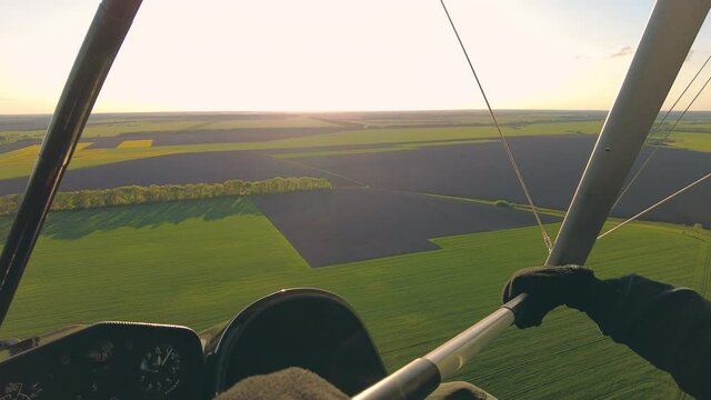 Motorized hang glider flying above field at sunset