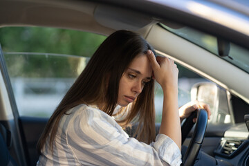 Sad young woman suffer from stress inside car. Upset unhappy female driver sit on front seat...