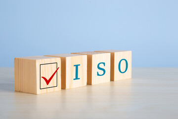 The abbreviation ISO on wooden cubes with check mark on blue background.