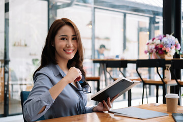 Portrait asian Businesswoman Working On digital tablet and reading on notebook In cafe coffee shop