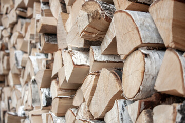 Preparation of firewood for the winter. View of the woodpile of firewood. Chopped firewood is randomly placed in a pile. The ends of chopped firewood close-up, side view.