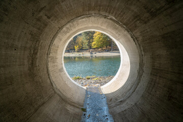 Inside view to the lake from a huge concrete drainage pipe for mountain river water
