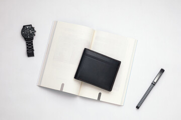 Fashionable black leather men's wallet with watch, blank book and pen on white office desk, white table. Work desk  view. Top angle work desk. Flat lay work desk