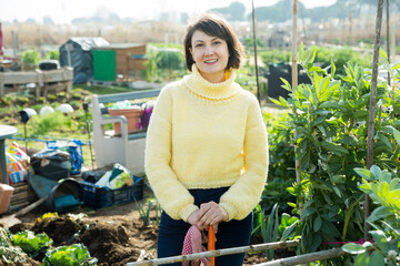 Portrait of female amateur gardener proud of her garden standing in homestead