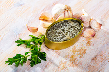 Eel fry with garlic in open tin can on wooden table. Popular and expensive delicacy