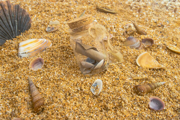 Glass bottle with a note on sand beach with shells, treasure and adventure concept