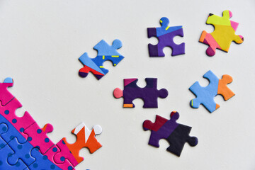 Fragment of a folded jigsaw puzzle and a pile of uncombed puzzle elements against the background of a white surface