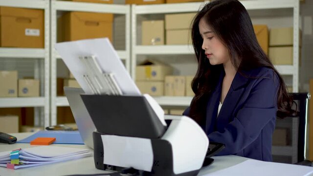 Asian women are using document scanners to transfer data to the laptop.