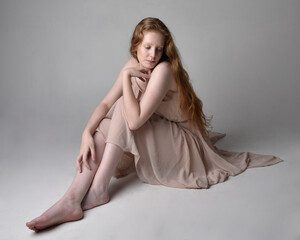 Full length portrait of pretty red haired woman dancer,  wearing skin toned flowing fairy dress....