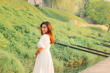 Asian woman standing on wooden pathway and looking to camera with nature background