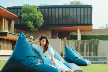 Beautiful Asian woman relaxing on blue bean bag chair on the grass near river