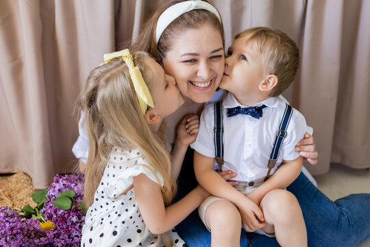 brother and sister kiss their mother. a smiling woman embraces two children. the concept of a happy family. Lifestyle. High quality photo