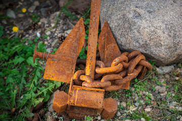 An old rusty anchor is lying on the ground.
