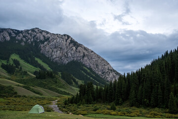 Tent with rocky mountains and cloudy sky on. background. Nature background. Wilderness background. Adventure travel concept. Komirshi gorge in Kazakhstan.