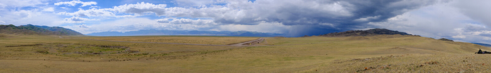 Fototapeta premium Panoramic view to steppe with mountains and cloudy sku on background.