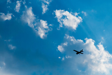 The plane was flying in the sky with white clouds.