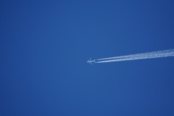  an airplane on a blue sky with vapor trails