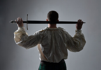 Close up portrait of handsome brunette man wearing Scottish kilt and renaissance white  pirate...