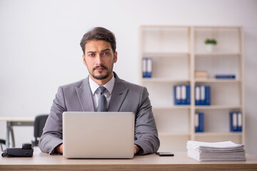 Young male employee and too much work in the office