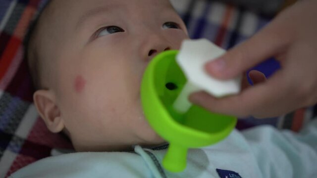 Infant play with teether toy hold by sister