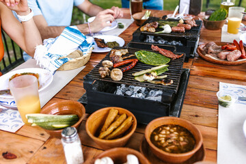 latin people eating Mexican food, Tacos, spicy salsa, tortillas, beer, snacks and peoples hands over wood table in a restaurant terrace in Mexico Latin America