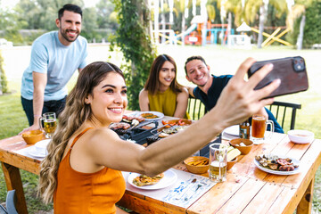 Group of latin friends taking a photo selfie and eating mexican food in the restaurant terrace in...