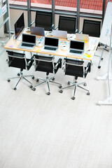 Conference meeting room working table in company office full of laptop notebook computers black hot coffee cups and report data paperwork documents and black chairs with copy space on wooden floor