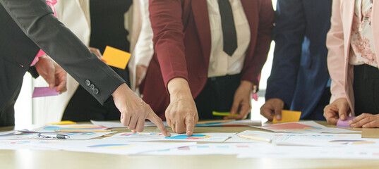 Group of unrecognizable businesswomen meeting together brainstorming at working desk, pointing fingers and analysis data chart and graph with self-confidence and full of knowledge exchange in team