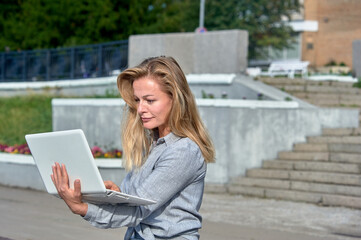 A woman with a laptop sits on a wooden platform, works online