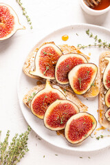 Breakfast with sweet bruschettas with figs and honey on a white plate