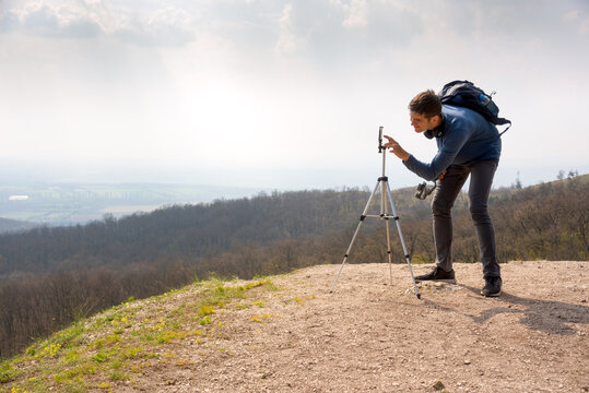 Young man taking landscape photo with mobile phone and tripod